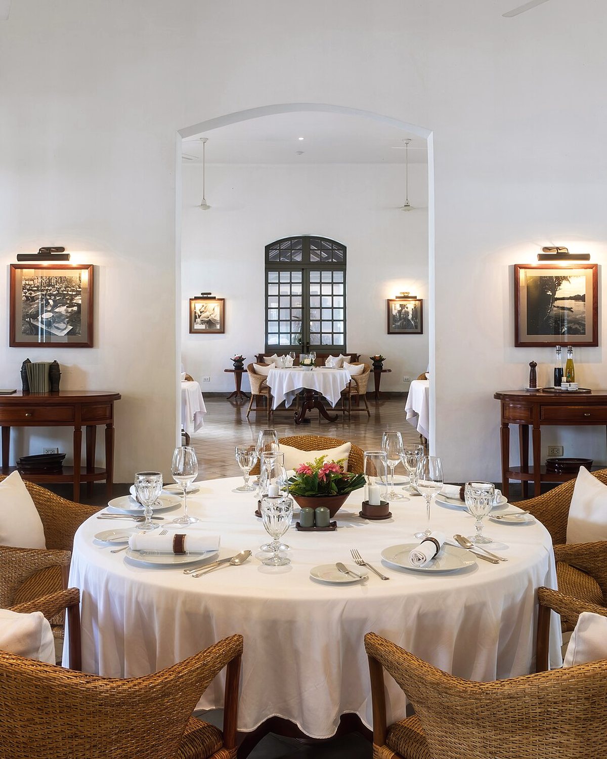La salle du restaurant, tables rondes nappées de blanc et portes-fenêtres ouvertes